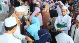 Salah seorang ibu menggendong bayinya untuk di kursi (cukur-red) oleh para Tuan Guru. (Istimewa)