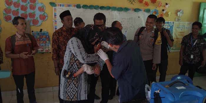 Seorang ibu menggedong anaknya yang diberikan vaksin polio oleh tenaga kesehatan Puskesmas Sembalun. (foto: ong)