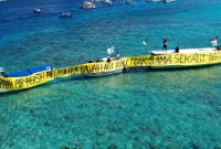 Warga Gili Meno bersama Walhi NTB membentangkan spanduk di laut sambil menuntut pipa air bersih usai tiga tahun krisis, Kamis 21 Mei 2026. (Foto: Lombokini.com).