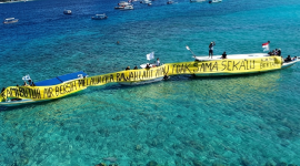 Warga Gili Meno bersama Walhi NTB membentangkan spanduk di laut sambil menuntut pipa air bersih usai tiga tahun krisis, Kamis 21 Mei 2026. (Foto: Lombokini.com).