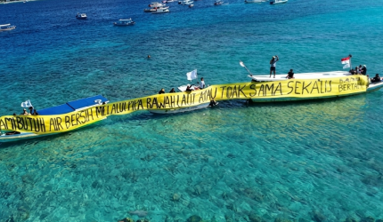 Warga Gili Meno bersama Walhi NTB membentangkan spanduk di laut sambil menuntut pipa air bersih usai tiga tahun krisis, Kamis 21 Mei 2026.