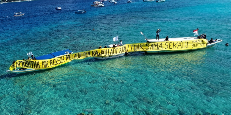 Warga Gili Meno bersama Walhi NTB membentangkan spanduk di laut sambil menuntut pipa air bersih usai tiga tahun krisis, Kamis 21 Mei 2026. (Foto: Lombokini.com).