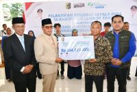 Bupati Lombok Timur, Haerul Warisin, didampingi Sekda dan Kepala Cabang BPJS Ketenagakerjaan, menyerahkan secara simbolis dana jaminan hari tua (JHT) senilai Rp 844 juta kepada perwakilan 87 kepala desa purna tugas Kabupaten Lombok Timur, Rabu 13 Mei 2026. (Foto: Lombokini.com).
