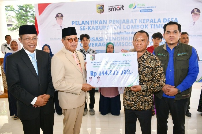 Bupati Lombok Timur, Haerul Warisin, didampingi Sekda dan Kepala Cabang BPJS Ketenagakerjaan, menyerahkan secara simbolis dana jaminan hari tua (JHT) senilai Rp 844 juta kepada perwakilan 87 kepala desa purna tugas Kabupaten Lombok Timur, Rabu 13 Mei 2026. (Foto: Lombokini.com).
