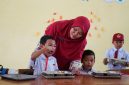 Seorang guru membagikan makanan Program Makan Bergizi Gratis (MBG) kepada siswa di salah satu sekolah. (Foto: Lombokini.com/Badan Gizi Nasional).