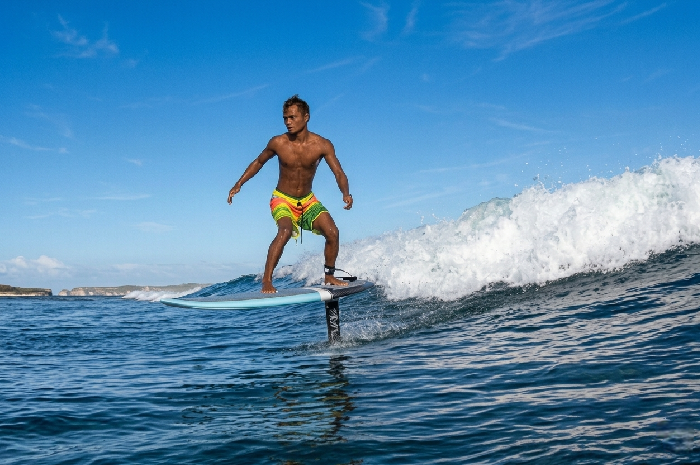 Seorang peselancar dengan lihai mengendarai papan selancar hydrofoil (foilboard) di atas ombak Teluk Ekas, Jerowaru, Lombok Timur.