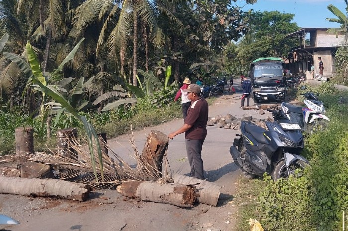 Warga Kalijaga Timur memblokir jalan lintasan truk galian C menggunakan batang kelapa, Ahad 16 Agustus 2026. Aksi ini mereka lakukan untuk mendesak perbaikan jalan rusak di wilayah tersebut. [Foto: Lombokini.com]