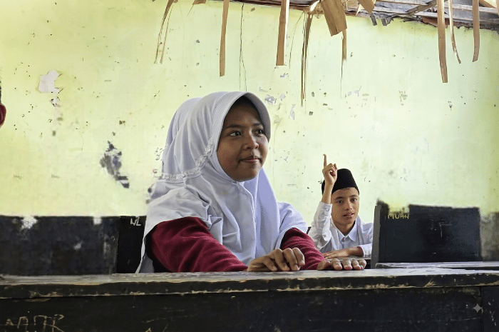 Ziadatun Nisa (14) menyimak pelajaran di ruang kelas MTs Nawarul'uyun, Lombok Timur, di tengah ancaman genteng-genteng atap yang nyaris roboh menimpa kepalanya.